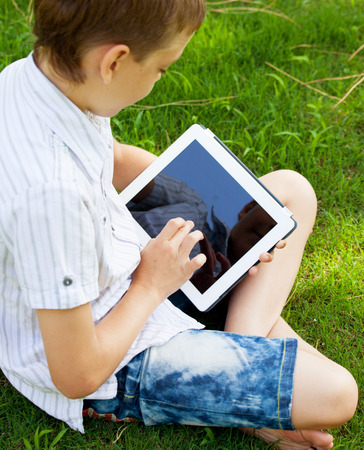 Boy with tablet outdoors. Child with pc computerの写真素材