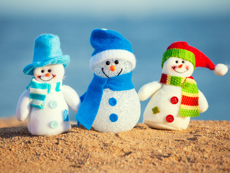 Snowmans on sand near sea. Christmas decoration. Vacationsの写真素材