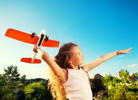 Child playing with plane. Happy girl play outdoorsの写真素材