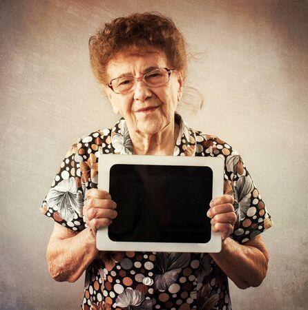 Old woman holding a tablet in the hands of. Seniors with tablen pcの写真素材