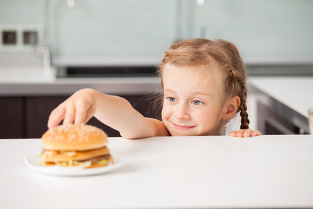 Child with hamburger at kitchenの写真素材