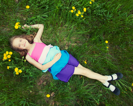 Child at summer. Happy girl outdoors on green grassの写真素材