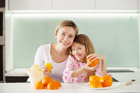 Mother and daughter make orange juice on a juicerの写真素材