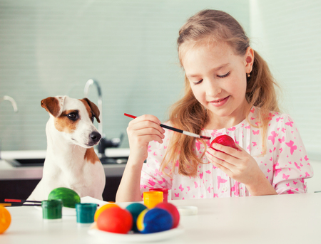 Easter. Child with dog painting eggsの写真素材