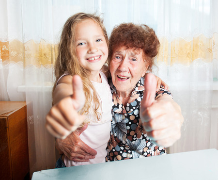 Senior with girl. Generation. Elderly woman with great-grandchild showing sign okの写真素材