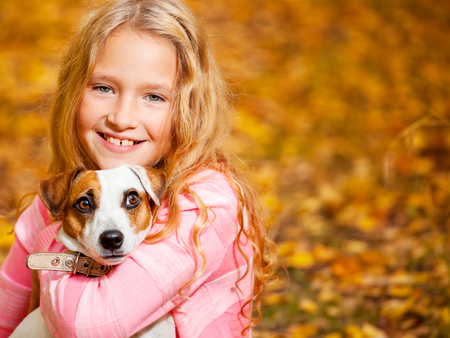 Girl with dog outdoors. Child with pet at autumnの写真素材