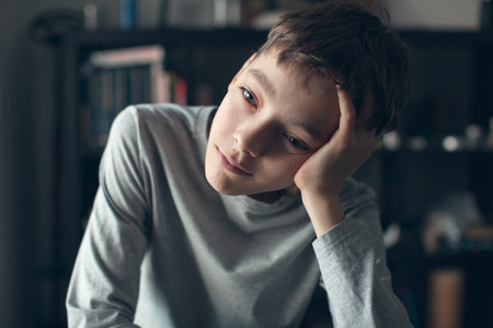 Sad boy. Depressed teenager at home. Problems at familyの写真素材