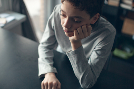 Sad boy. Depressed teenager at home. Problems at familyの写真素材