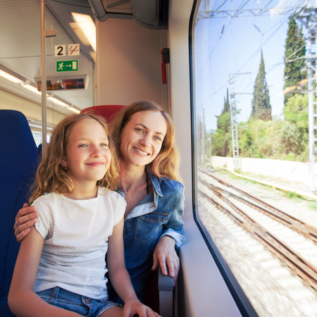 Woman with child traveling by pablic transport. Family travelling in a train and looking through the windowの写真素材