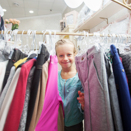 Child in a children's store. Happy girl choosing clothesの写真素材
