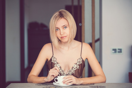 Female in a home clothes drinking coffee. Woman in nightie morningの写真素材