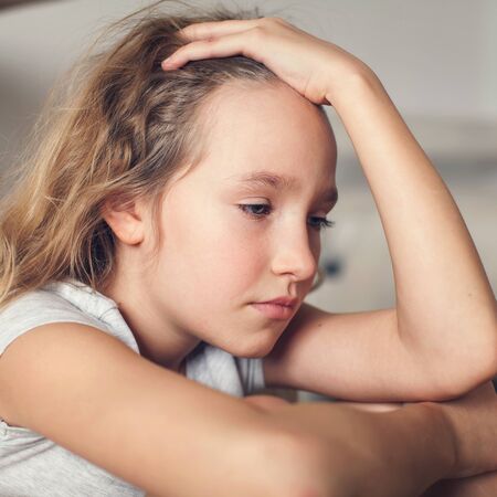 Sad child at home. Abuse. Depression girl indoorsの写真素材