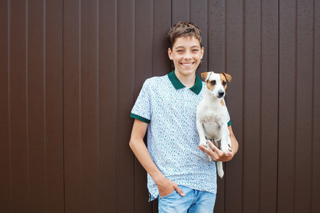 Happy teen with dog. Boy and pet outdoors. Friendship