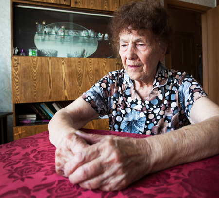Old woman. Elderly sad female at home
