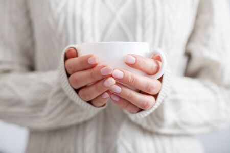 Coffee mug in female hands. Woman drinking hot coffeeの写真素材