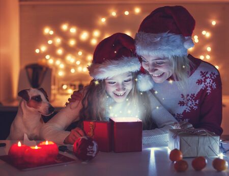 Mom with daughter open christmas gift. Happy familyの写真素材