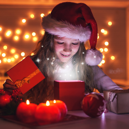 Child opens a New Year's gift. Happy girl. Christmas miracleの写真素材