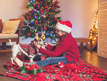 Smiling child with dog near christmas tree at home. Merry christmas and happy New year!の写真素材