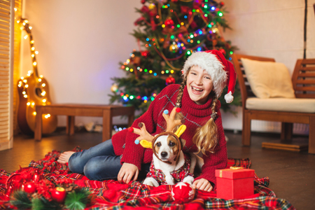Smiling child with dog near christmas tree at home. Merry christmas and happy New year!の写真素材