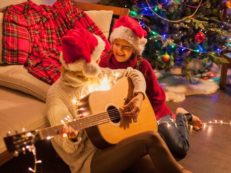Child with mom near christmas tree at home. Merry christmas and happy New year!