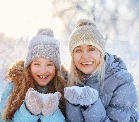Family at winter. Happy girl  with mother outdoors. Woman with kid on snowの写真素材