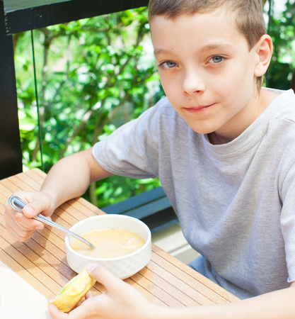 Child eating soup at cafeの写真素材