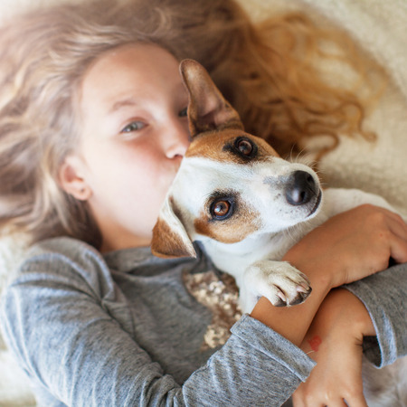 Happy child with dog. Portrait girl with pet. Jack Rassell with teen embracingの写真素材