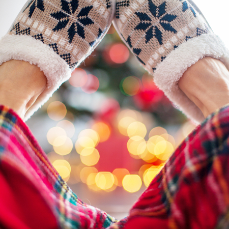 Legs in slippers on Christmas tree backgroundの写真素材