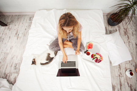 Young woman with laptop in the bedの写真素材