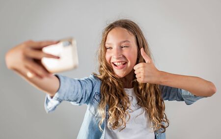 Smiling teen making selfie photo on smartphone over white background  cute girlの写真素材