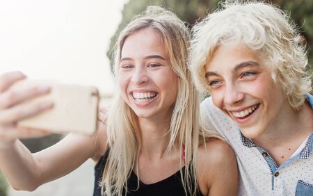 Young smiling couple taking a selfie portrait on mobile phone. Happy teens on holiday