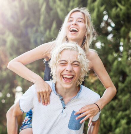 Young happy smiling teen couple embracing on green park background. Boy and girl laughing
