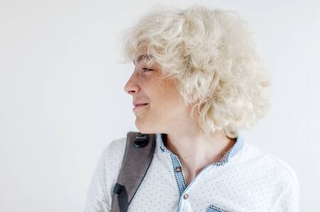 Portrait of cheerful young blond man smiling looking away. Happy teen at studio