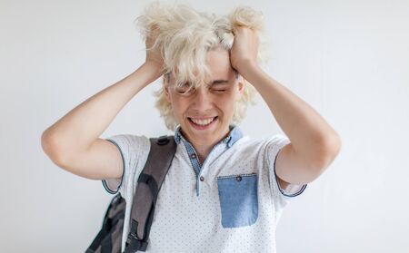 Frustrated student covered his face with his hands. Sad teen at white background