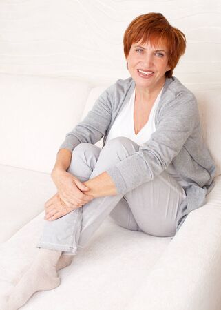 Happy mature female on sofa. Smiling middle woman at homeの写真素材