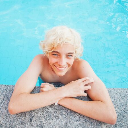 Handsome in the pool outdoor. Happy teen boy at summer holiday