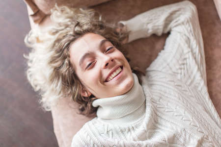 Happy laughing young man. Portrait of a teen resting on a sofa