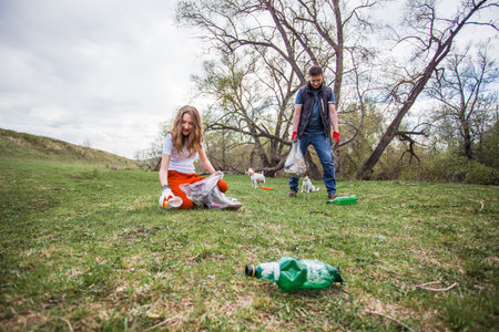 People collect garbage and plastic bottles in the forest. Man and girl clean park of garbage Global problem of environmental pollutionの写真素材