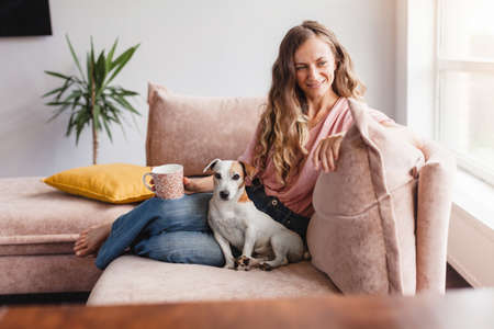 Calm and peaceful middle-aged woman takes a break, rests with a cup of hot tea on the couch at home....