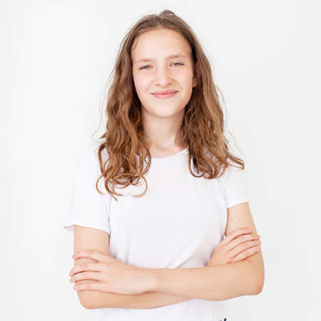 Portrait of young beautiful cute cheerful girl smiling looking at camera over white background. Happy teen in white t-shirtの写真素材