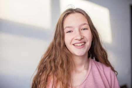 Portrait of young beautiful cute cheerful teen girl smiling looking at camera over white backgroundの写真素材