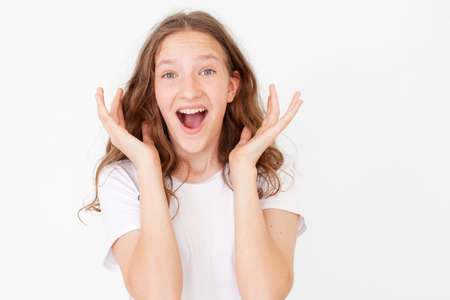 Cheerful happy young beautiful girl looking at camera smiling laughing over white background. Happy teen in white t-shirtの写真素材