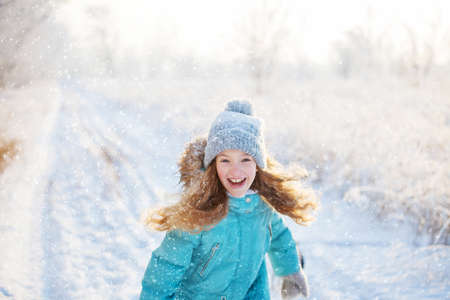 Child walking at winter park. happy girl on snowの写真素材