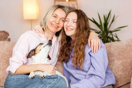 Smiling loving young Caucasian mother relax on couch with teen daughter chat and talk. Happy caring...
