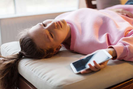 Frustrated sad woman lying on couch with smartphone, bad news, unhappy teen girl breaking up with...