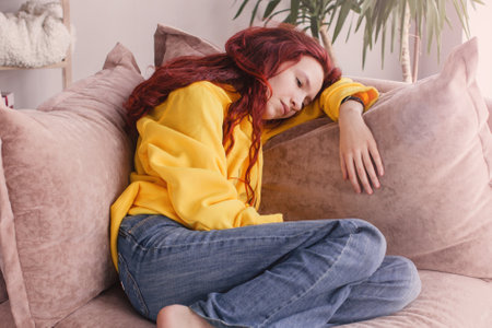 Sad depressed young adult woman crying alone at home, upset desperate teen girl in tears trouble feeling stressed ashamed worried about problems sit on sofaの写真素材