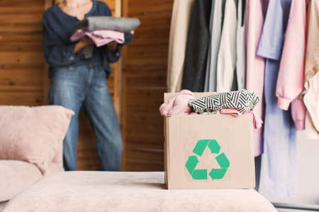 Female put stack things clothes in cardboard recycle box, recycle conceptの写真素材