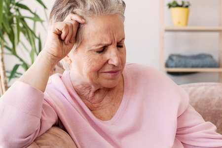 Pensive thoughtful middle aged lady looking away sit alone at home feel anxious lonely, sad depressed melancholic old mature woman suffer from sorrow grief thinking of problem suffer from solitudeの写真素材