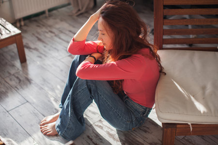 Sad depressed young woman feeling bad down on couch at home. Hopeless alone, upset teen female victim in trouble being heartbroken offended abused, having problem addiction, girl in despair conceptの写真素材