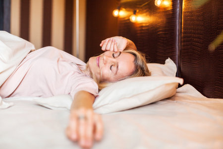 Good morning, new day, weekend, holiday. Happy middle aged woman sits on bed, lady stretching arms after sleep and enjoying morning in cozy comfort bedroom interior, free spaceの写真素材